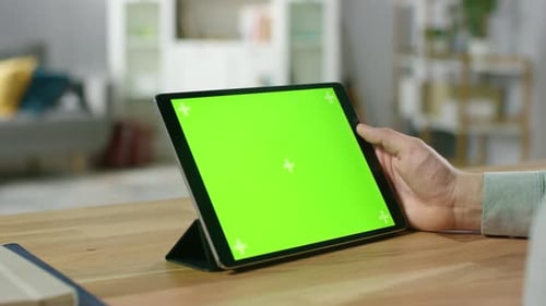 Man Watching Green Mock-up Screen Digital Tablet Computer While Sitting at the Desk. Man Watching V