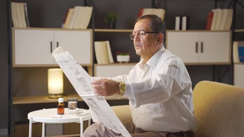 Mature Man Reading Newspaper Indoors During the Day