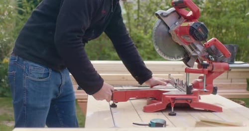 Man Cutting Lumber with Chop Saw Outdoors