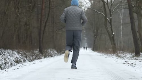 Junger Mann joggt alleine durch ein verschneites Winterwaldtrailtraining