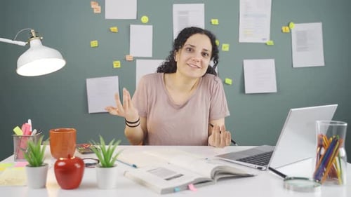 Woman Gesturing and Talking in Workplace with Laptop