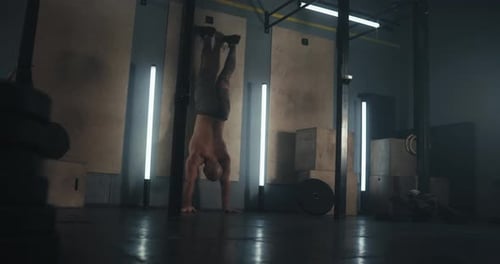 Muscular Man Doing Handstand Pushups Against Wall
