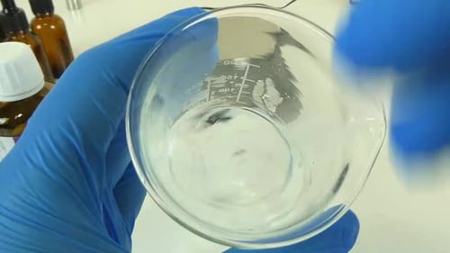 Vidéo présentant le processus consistant à secouer un sérum clair et transparent dans un bécher en verre dans un professi