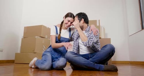 Portrait of a couple in love seated on the floor and they just bought a house and are moving. The