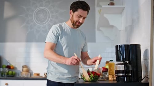 Man Mixing Salad in Bright Kitchen at Home
