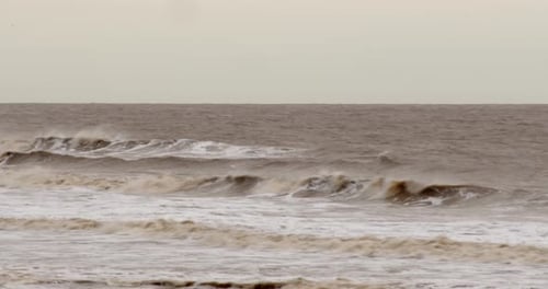 cold bleak looking winter waves breaking on to Ingoldm musicells, Skegness sandy beach