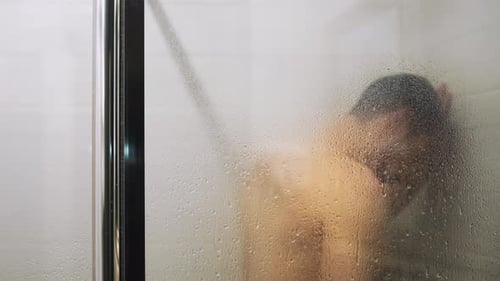 Man in steamy shower with condensation on glass