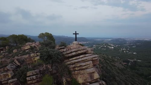 Cross on Rocky Cliff Overlooking Vast Landscape