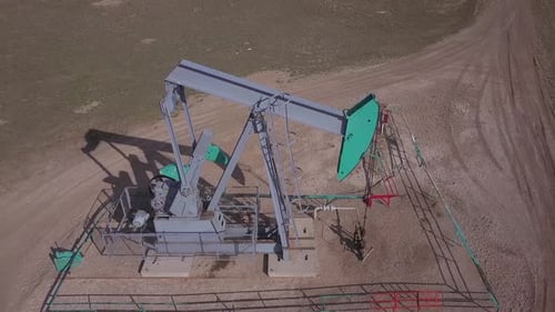 Aerial flyover of small pumpjack pumping oil from a Canadian oilfield