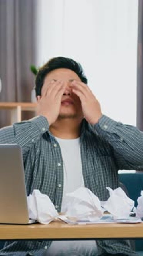 Tired Adult Asian Man Waking Up Stretching His Hands and Continuing to Work on Laptop on Office