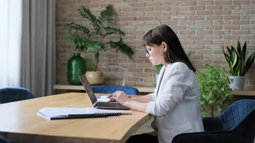 Reife Geschäftsfrau arbeitet im Büro und tippt auf einem Laptop