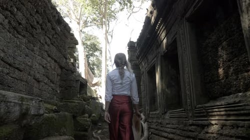 Beautiful woman walking through ancient ruins of old stone temple in Cambodia