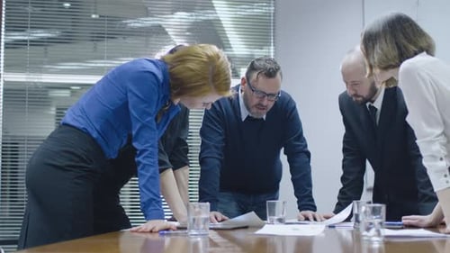 Team Examines Documents in a Bright Conference Room