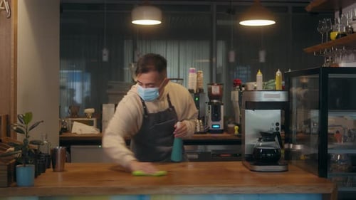 Young Asian Man Waiter Barman or Worker in Cafe Restaurant Cleaning Bar Counter with Duster While