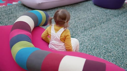 Child Sitting on Colorful Beanbag in Playroom