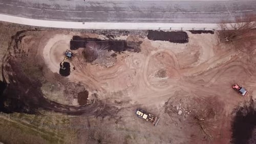 Heavy machinery working in a construction site and driving around. birds eye view moving further awa