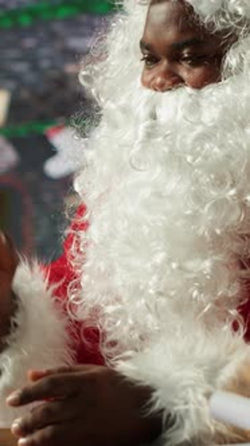 Vertical Video Father Christmas Checking Online Gift Lists on a Tablet in Cozy Festive Workshop