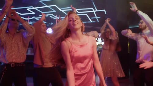 Group of Young Friends Dances Together in Neon Light of Night Club