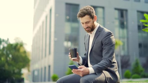 Bearded Man in Suit Sits and Uses Phone