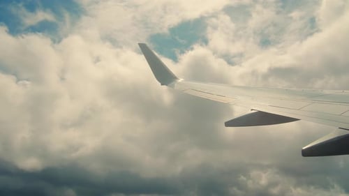 Aircraft Plane Wing of Flying in Clouds and Blue Sky Airplane As Seen By Passenger Through Porthole