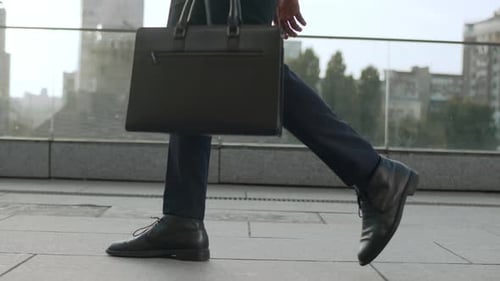 Unrecognizable businessman walking to work in the city street in slow motion