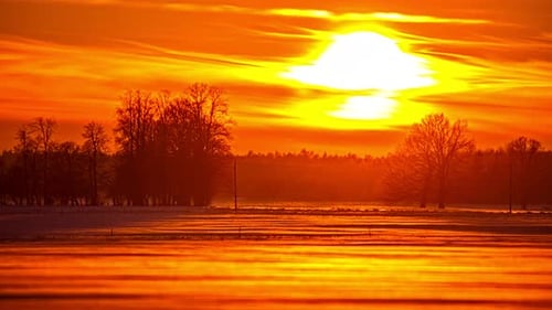 bright orange sunset reflecting on snow surface at winter meadow. timelapse shot