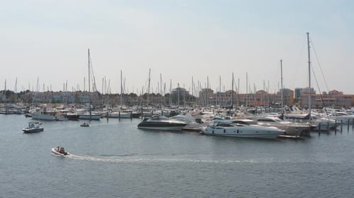 Cinematic drone / aerial shot of three boats on a marina in the background with sailing boats on a s