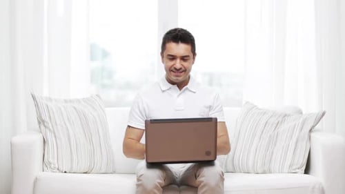Man Sitting on Sofa Using Laptop Indoors