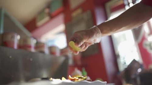 Gloved Hand Squeezing Lime on Food Preparation
