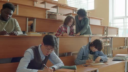 Teacher Helping College Student With Task