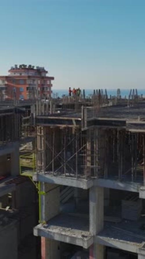 Vertical Video of Residential Construction With a Crane Assisting in Wall Assembly and Concrete