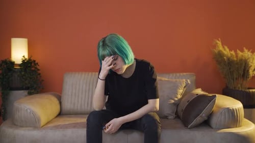 Depressed young woman covering her face with her hand.