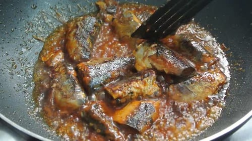 Sardines being cooked in pan, close up