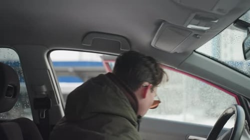 Boy Leaves Car in Winter Urban Setting Seen From Interior View