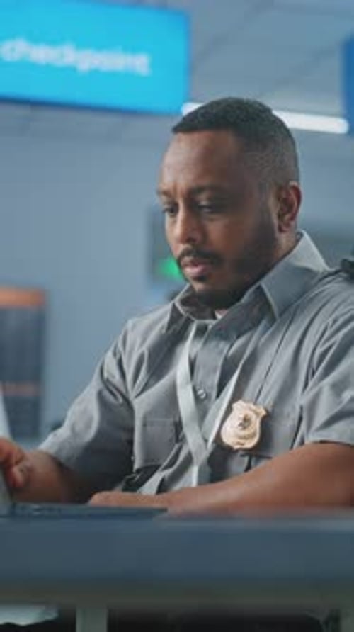 Airport Security Checkpoint Security Officer Using Laptop Computer Looking at Camera
