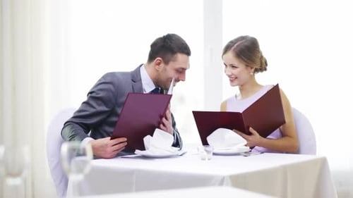 Restaurant, Couple, Relationship and Holiday Concept - Smiling Couple with Menus At
