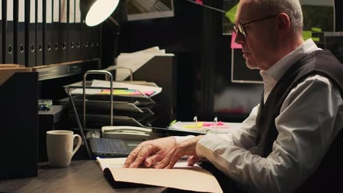 Man Reviews Paperwork at Overcrowded Desk