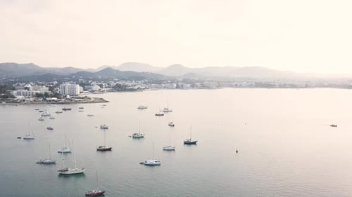 Cinematic drone footage of Sant Antoni de Portmany sea bay with sailboats. Ibiza, Balearic Island, S