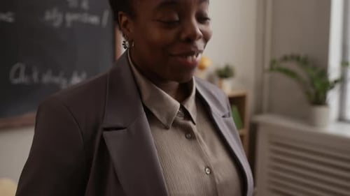 Teacher Holding Tablet Device, Smiling in Classroom Setting