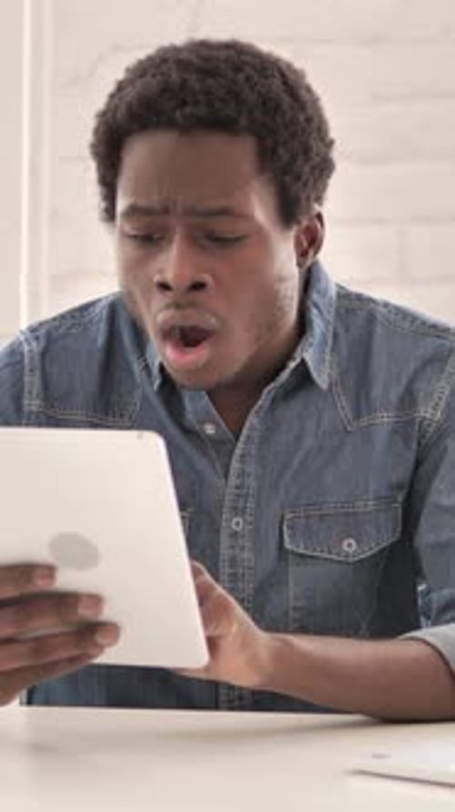 Man Reacting to Content on Tablet Device Indoors