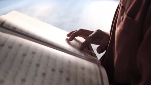 Offener Koran mit arabischer Schrift sichtbar, religiöses Buch mit arabischer Schrift ist der Koran, muslimischer Mann