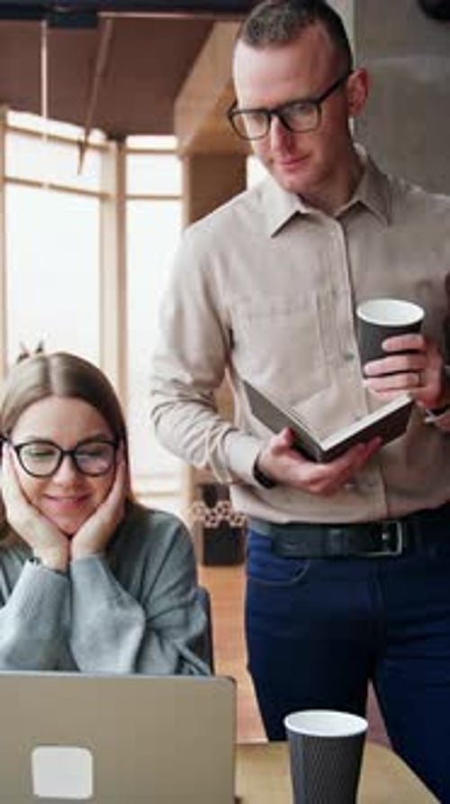 Woman at Laptop Discussing Notes with Man