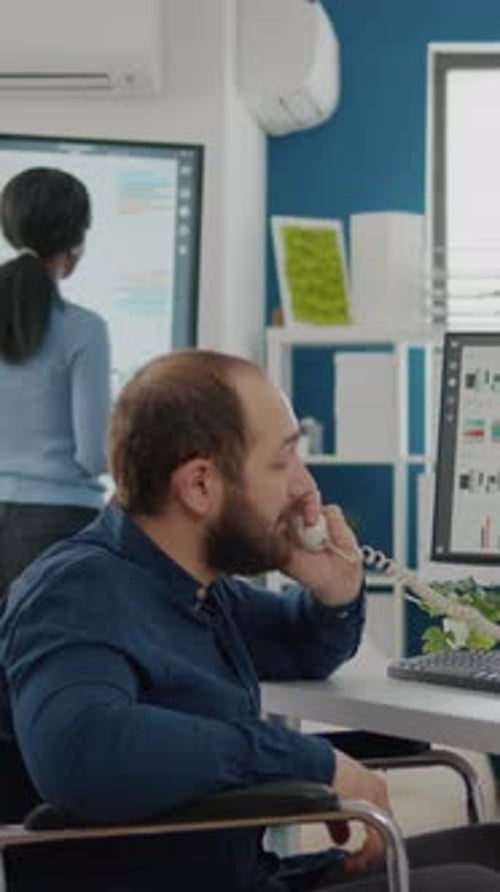 Man in Wheelchair Answering Telephone in Office