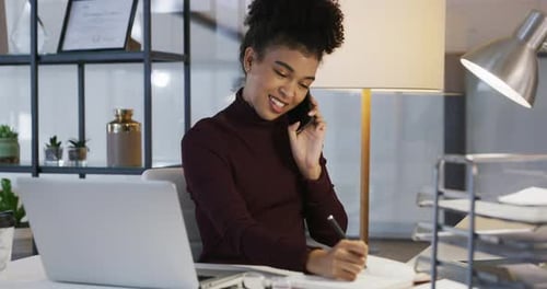 4k video footage of young businesswoman using a laptop and smartphone in a modern office