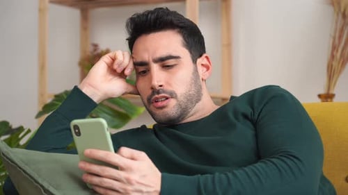 Man Using Phone While Relaxing on Couch Indoors