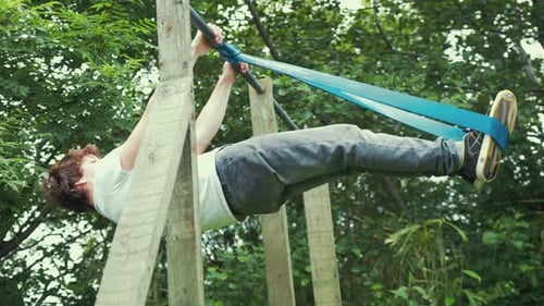 Junger Mann führt Krafttraining mit dem Vorderhebel-Krafttraining mit Widerstandsband zu Hause im Freien durch