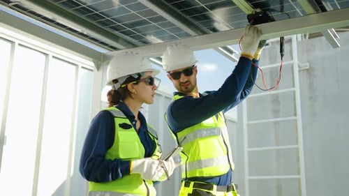 Zwei professionelle Solarenergietechniker inspizieren Photovoltaikmodule auf einem hellen Dach