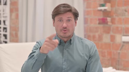 Man Speaking and Gesturing at Camera Indoors