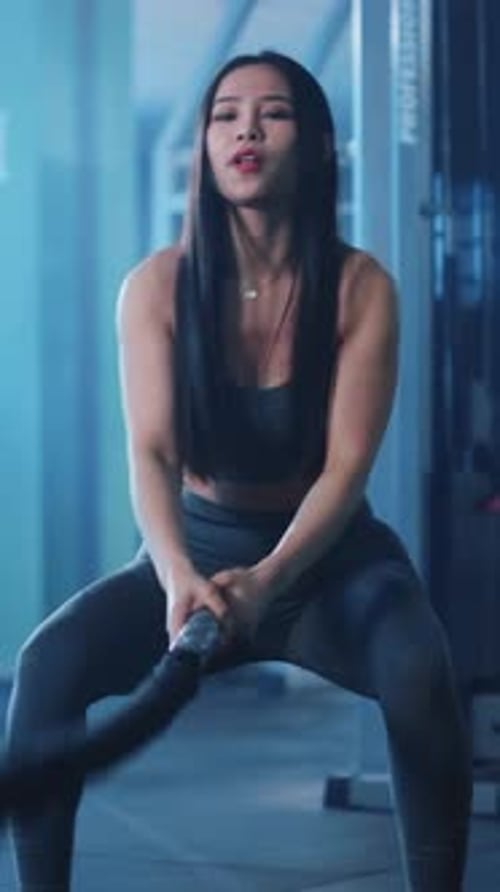 Athletic woman with battling ropes in gym