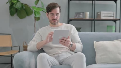 Man Using Tablet While Relaxing on Couch